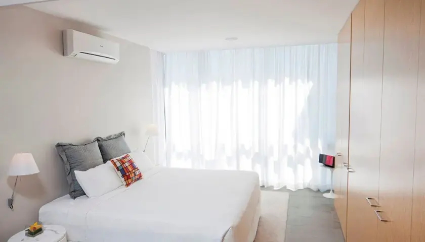 Un dormitorio moderno con aire acondicionado en la pared, ideal para saber donde colocar el aire acondicionado en un dormitorio.