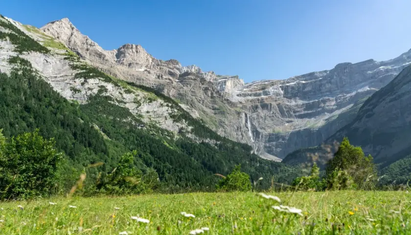 Majestuoso circo de Gavarnie con cascada y prado verde.