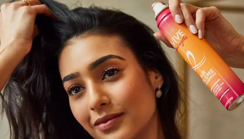 Mujer usa spray para disimular pelo sucio, dándole volumen y frescura al instante.