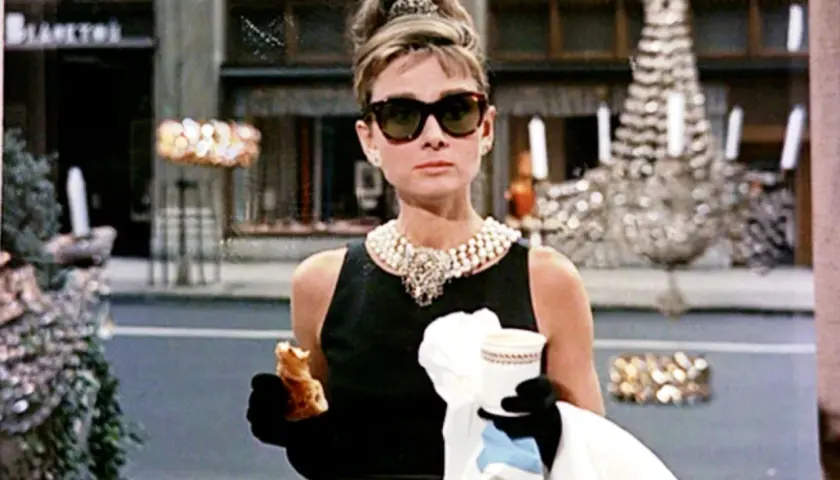 Holly Golightly, icona di stile, gusta un croissant davanti a Tiffany. Le sue recensioni su "Colazione da Tiffany" sarebbero sicuramente positive!
