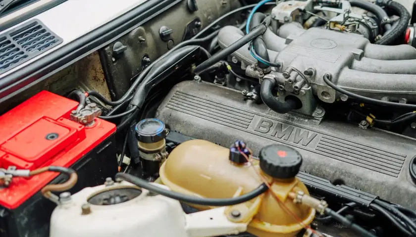 Silnik BMW z widocznym numerem OEM po VIN. Czerwony akumulator i zbiorniczek płynu chłodniczego.