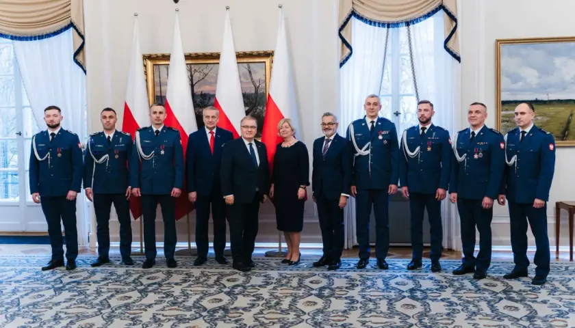 Grupa osób w mundurach i garniturach, być może związana z sekrety ochrony prezydenta i incydenty z drona pod rezydencją w marcu 2026.