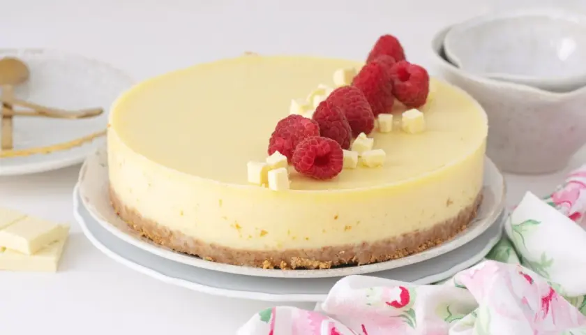 Deliciosa tarta de chocolate blanco, decorada con frambuesas frescas y trocitos de chocolate. ¡Un postre irresistible!