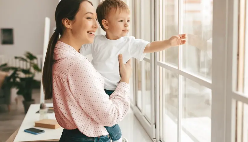 Mamma e bambino guardano fuori dalla finestra. Un giorno, potremo rifare gli infissi a costo zero e godere di una vista ancora più bella.