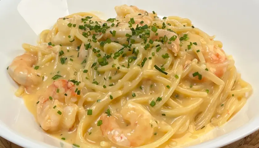 Spaghetti cremosi con gamberi e una spolverata di erba cipollina, un'invitante carbonara di mare.