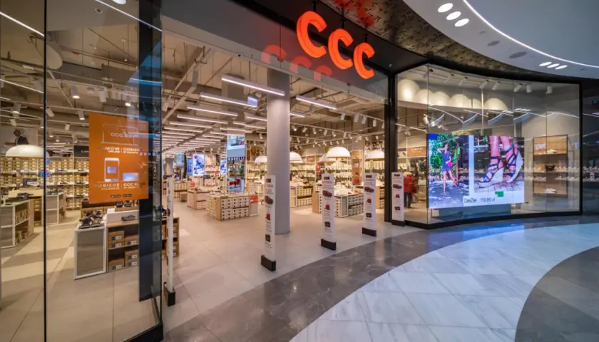 Wejście do sklepu CCC z widocznym logo, półkami z butami i ekranem LED.