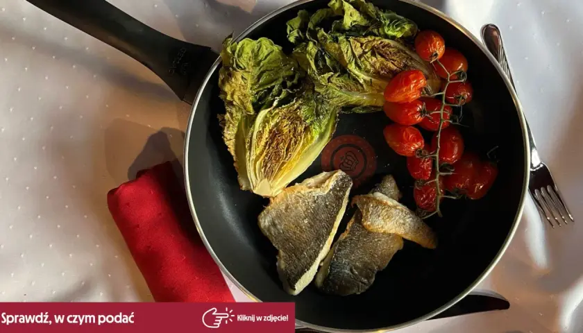 Smażona dorada z pomidorkami koktajlowymi i sałatą rzymską na patelni.