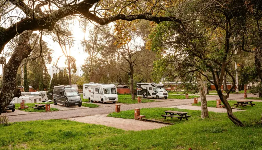 Autocaravanas y furgonetas aparcadas en un camping cerca de Lisboa, bajo la luz dorada del atardecer.