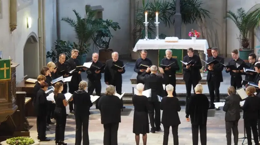 Chor singt in Kirche. Ein Dirigent leitet. Hier finden Sie kirchenmusik stellenangebote.