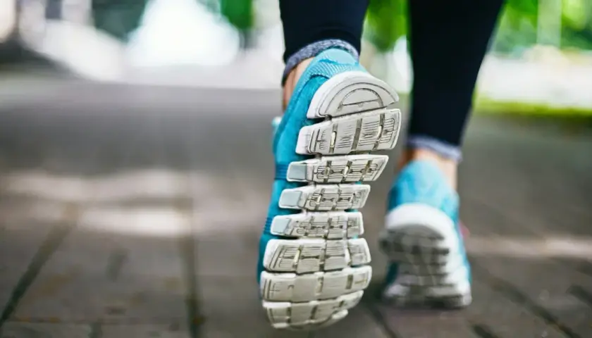 Niebieskie buty sportowe na chodniku, gotowe na szybki marsz czy bieganie.