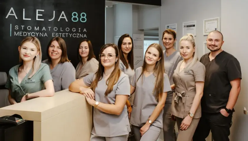 Zespół uśmiechniętych dentystów i personelu medycznego w gabinecie stomatologicznym.