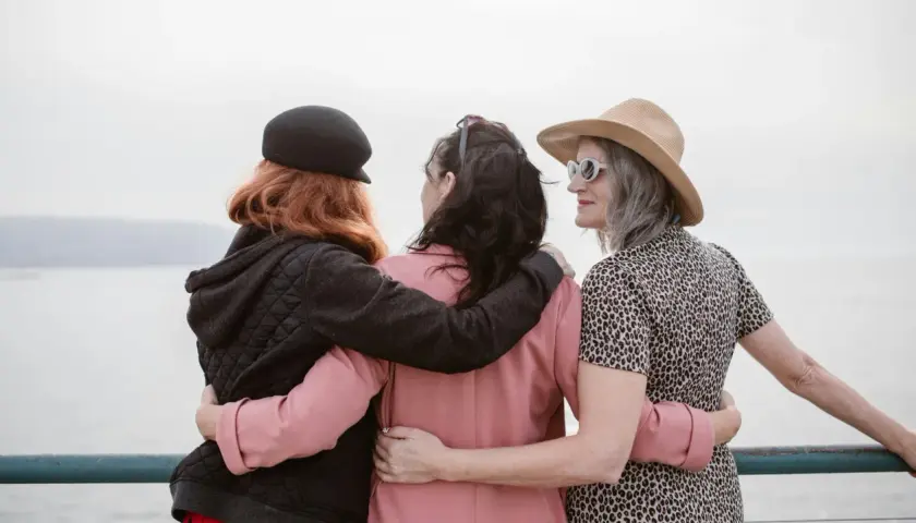 Drei stilvolle Frauen, die sich umarmen, zeigen, dass man auch ab 40 neue Freunde finden kann.