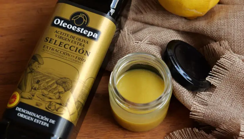 Ingredientes para una vinagreta de mostaza: botella de aceite de oliva virgen extra, un tarro con la vinagreta y un limón.