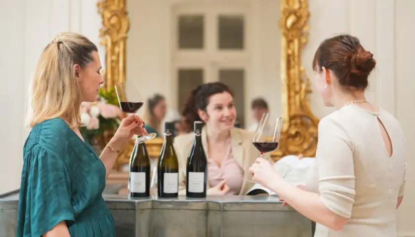 Trois femmes profitent d'une dégustation de vin au Château de Pommard, admirant le contenu de leurs verres.