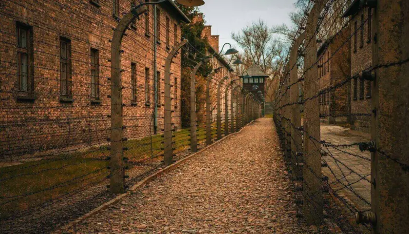 Ścieżka w Auschwitz, gdzie jest, prowadzi między ceglanymi budynkami i drutem kolczastym.
