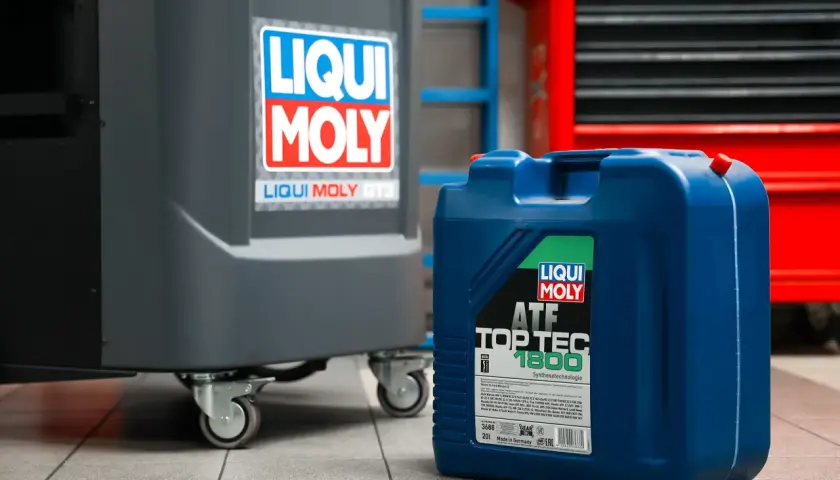 Niebieski kanister z olejem Liqui Moly ATF Top Tec 1800 w warsztacie. Zastanawiasz się, ile bierze mechanik za wymianę oleju?