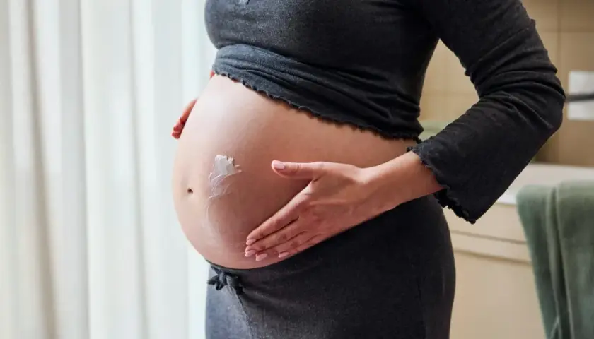 Gravid mage med kräm som smörjs in. Hudvård gravid är viktigt för att ta hand om huden under graviditeten.