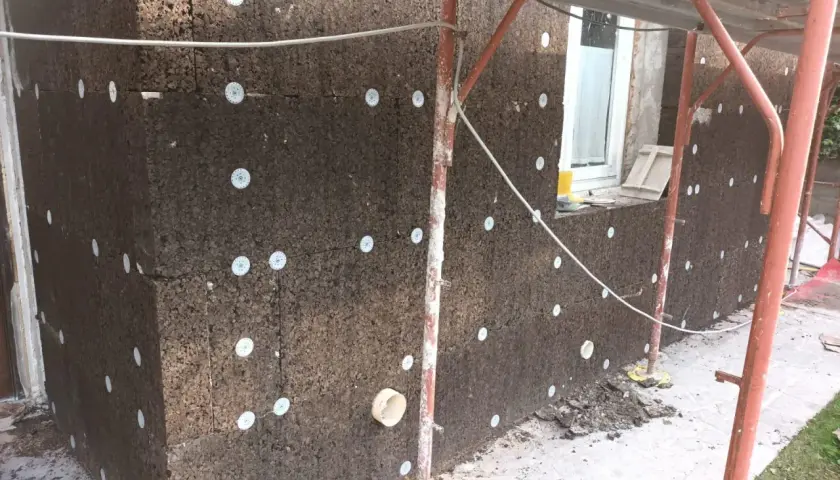 Pannelli di sughero espanso per cappotto termico, fissati con dischi bianchi. Lavori in corso su un edificio.