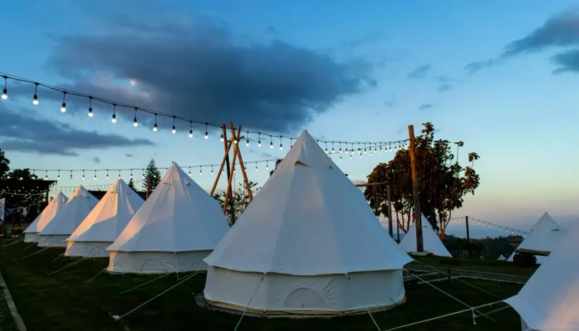Nocleg w namiotach typu dzwon, oświetlonych girlandami. To właśnie glamping co to – luksusowy kemping w otoczeniu natury.