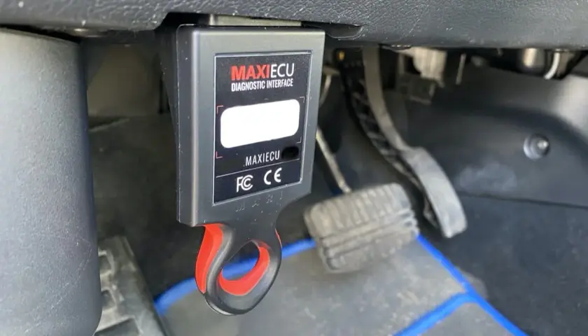 Interfejs diagnostyczny MaxiECU podłączony do portu OBD w Dacia Duster.