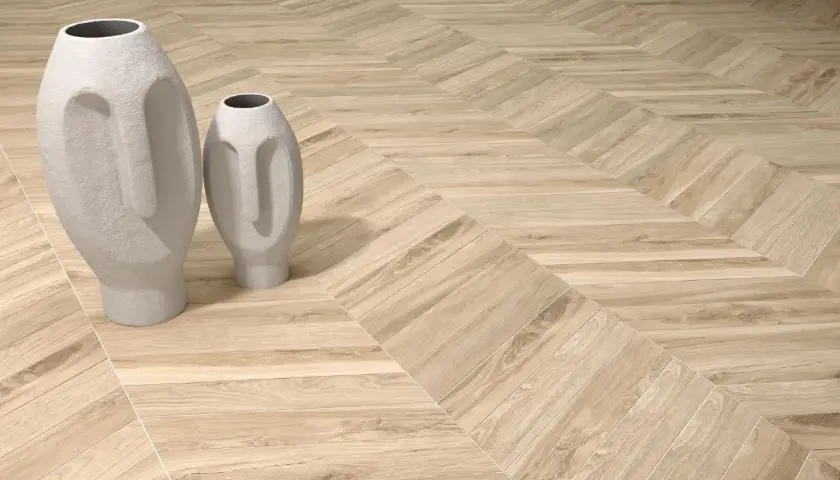 Dwie białe wazony w kształcie twarzy stoją na podłodze z drewnianymi deskami ułożonymi we wzór herringbone.
