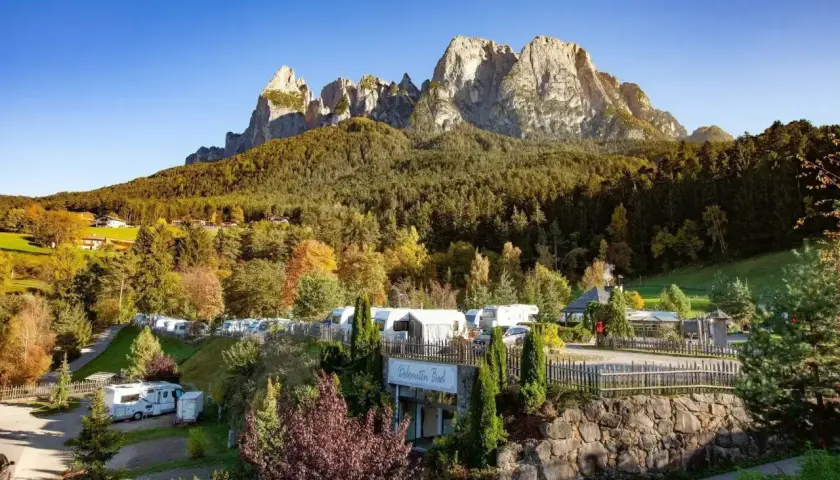 Malowniczy camping Seiser Alm z kamperami i przyczepami pod majestatycznymi szczytami Dolomitów.