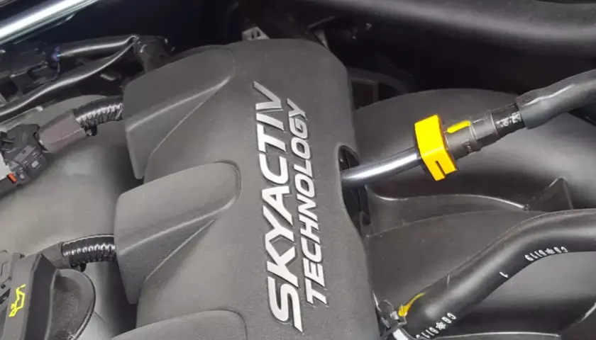 Silnik SKYACTIV TECHNOLOGY, jeden z najlepszych silników benzynowych, z widocznymi przewodami i złączkami.