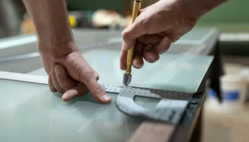 Ręce precyzyjnie tną materiał przypominający szkło, być może akryl. To co to za materiał, okaże się po obróbce.