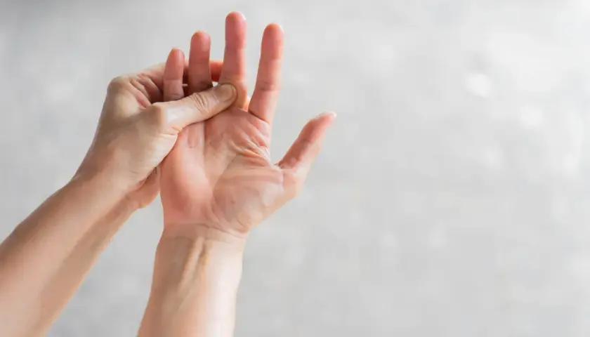 Mani che si massaggiano le dita, un gesto per alleviare il formicolio nel corpo causato dallo stress.