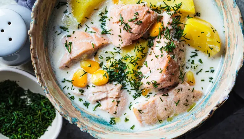 Łosoś w śmietanowym sosie z ziemniakami i kukurydzą, posypany koperkiem. Danie wygląda apetycznie, choć norwegia ceny w restauracjach mogą być wysokie.