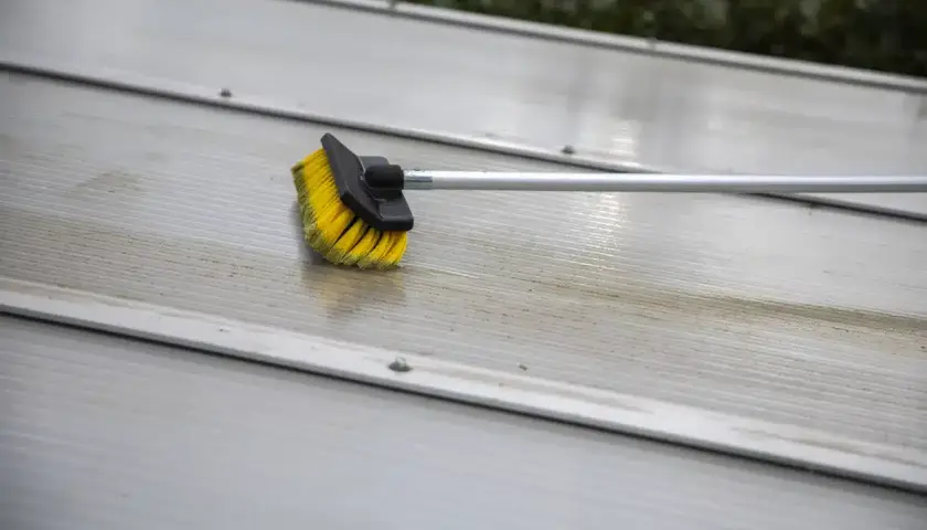 Brosse jaune et noire sur une surface striée en aluminium, en cours de nettoyage.