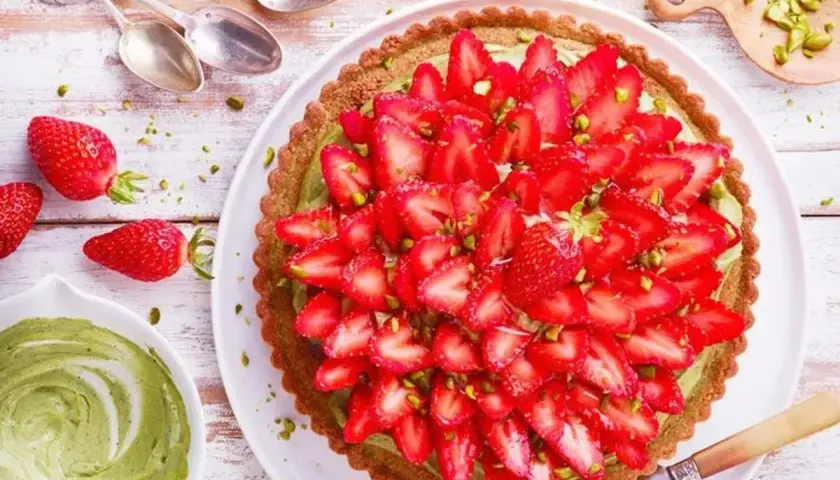 Tarte aux fraises sur pâte brisée, garnie d'une crème verte et de pistaches concassées. Un délice fruité et croquant.