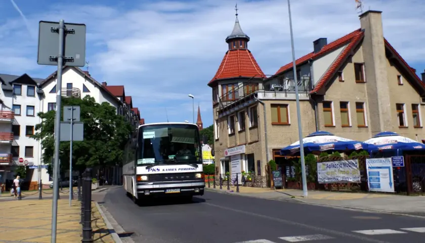 Autobus PKS w Międzyzdrojach zbliża się do dworca kolejowego. Słoneczny dzień, budynki z czerwonymi dachami.