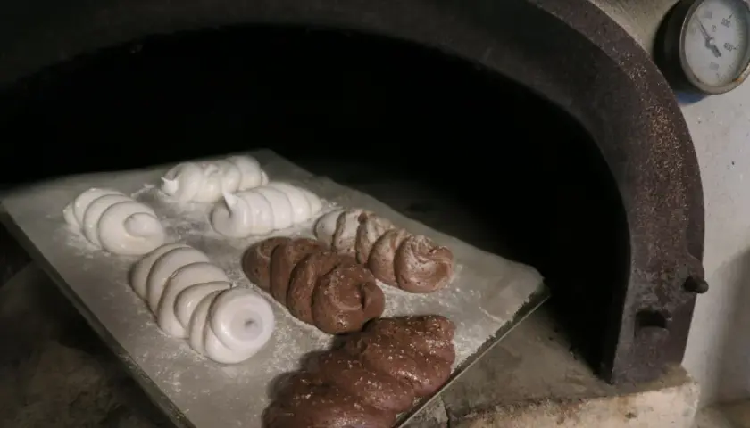 Des meringues blanches et chocolatées sont en cours de cuisson dans un four rustique.