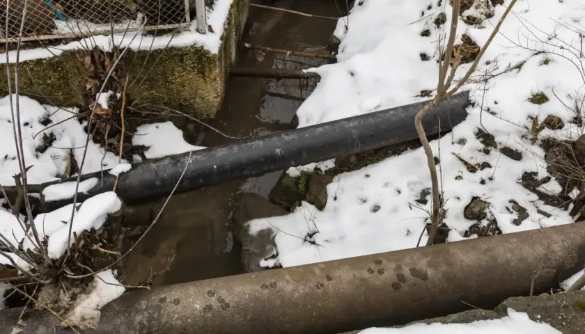 Zimowy krajobraz z rurami i strumieniem. Warto pamiętać, przy jakiej temperaturze pękają rury, by uniknąć awarii.