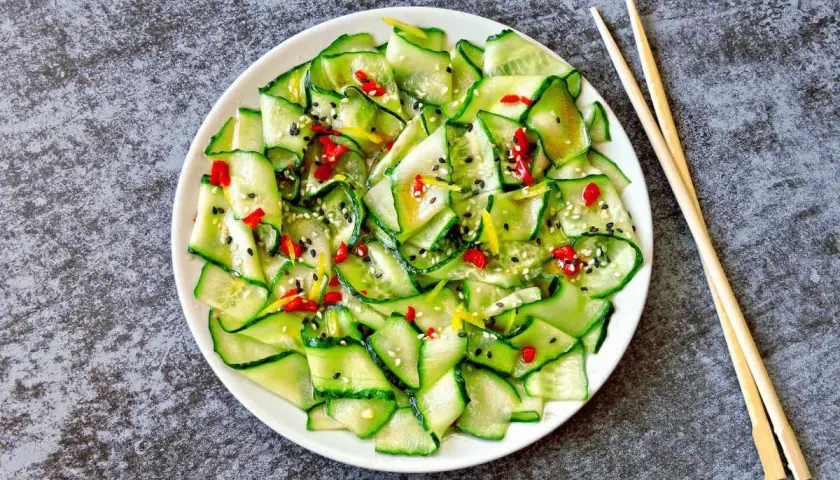 Insalata di cetrioli affettati sottili, condita con peperoncino, sesamo e scorza di limone. Un'idea fresca per le tue ricette con cetrioli.