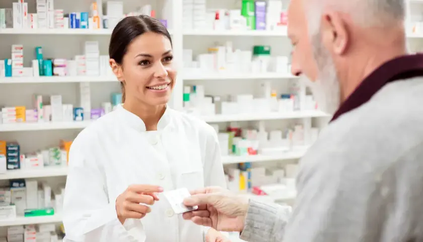 Farmaceutka podaje starszemu panu leki, doradzając mu atoris zamienniki.