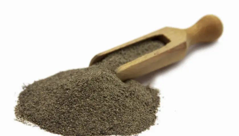 Stos mielonego pieprzu czarnego 1kg na drewnianej łyżce, gotowy do przyprawienia potraw.