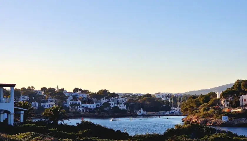 Blick auf die malerische cala d'or altstadt mit weißen Häusern, grünen Pinien und dem blauen Meer.