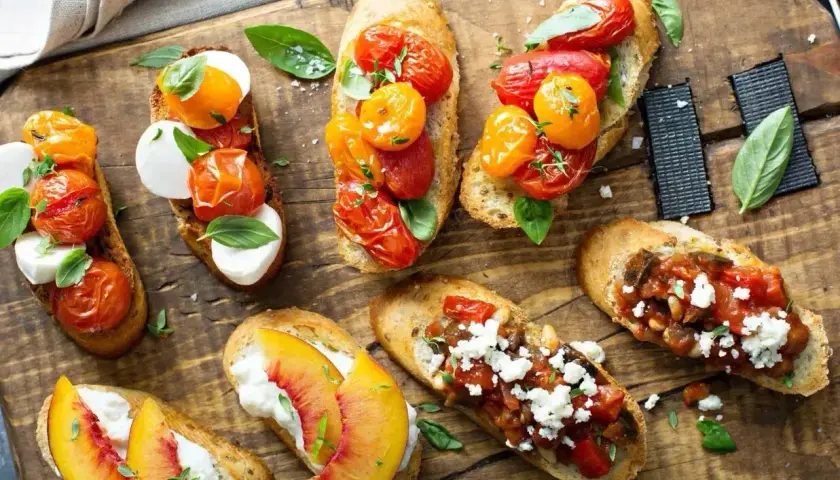 Letnie przekąski na grilla: bruschetty z pomidorkami, mozzarellą, brzoskwiniami i fetą. Idealne na przyjęcie w ogrodzie.