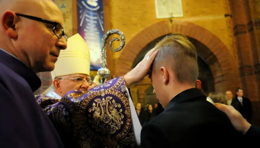 Biskup udziela sakramentu bierzmowania. Zastanawiasz się, ile dać na bierzmowanie? To ważny moment dla młodego człowieka.
