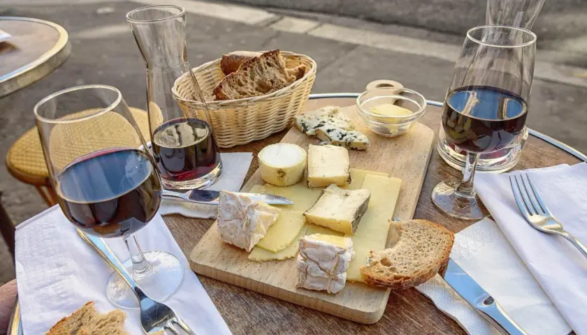 Un plateau de fromages variés, du pain et du vin rouge, une scène qui raconte une belle histoire de la cuisine française.