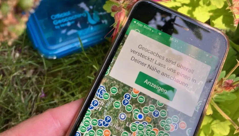 Smartfon pokazuje mapę z ukrytymi skarbami. To właśnie geocaching – zabawa w poszukiwanie skrytek z pomocą GPS.