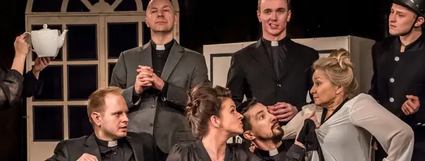 Na scenie Teatru Capitol rozgrywa się intryga. Aktorka w stroju pokojówki trzyma dzbanek, a wokół niej zgromadzeni mężczyźni w sutannach i jeden w stroju lokaja.