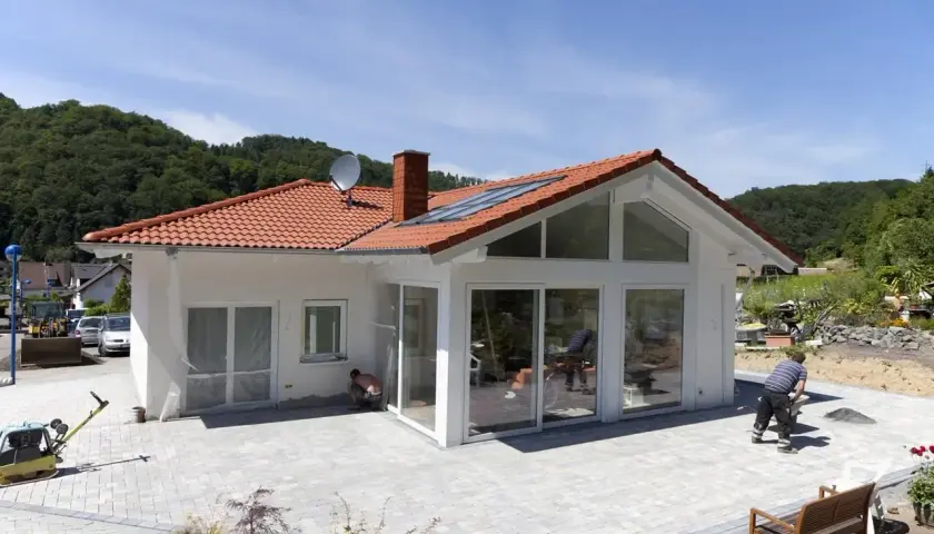 Nowy dom z ogrodem, gdzie działka jako wkład własny pozwoliła na realizację marzeń. Trwa układanie kostki brukowej.