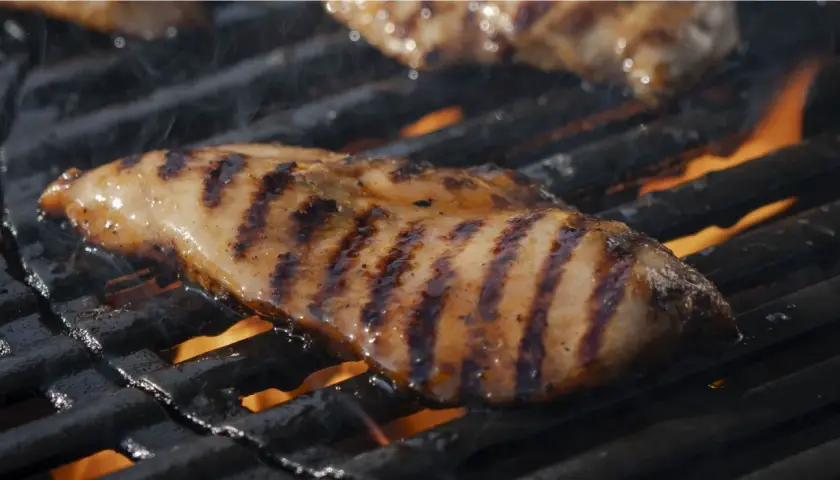 Saftig kycklingfilé med fina grillränder som grillas över öppen eld.