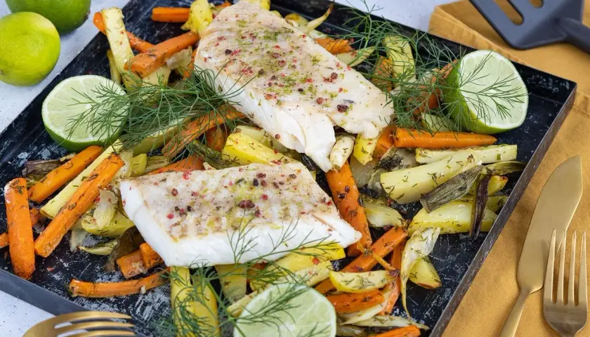 Pyszny mintaj z piekarnika z pieczonymi warzywami, limonką i koperkiem.