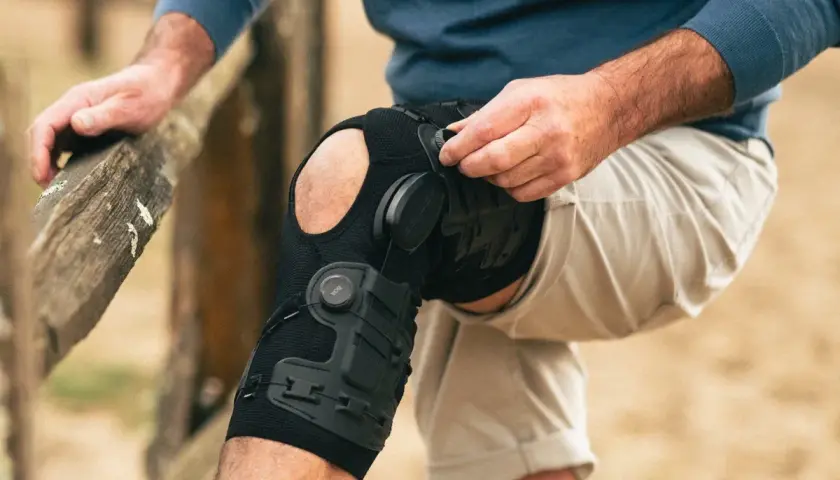 Mann legt eine DONJOY Schiene am Knie an. Die Schiene stützt das Bein für mehr Stabilität.