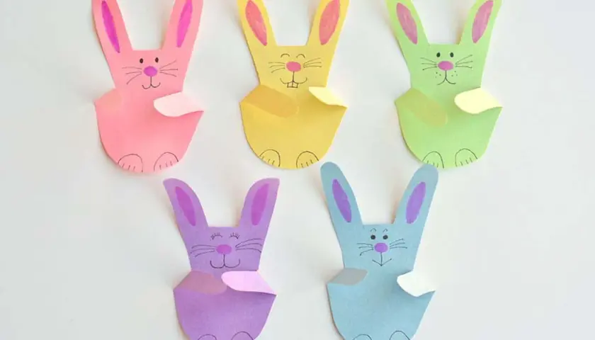 Fünf bunte Papierhasen, jeder ein einfacher hase, sitzen nebeneinander.