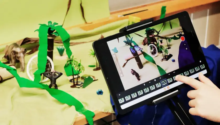 Kinder erstellen im Rahmen eines Stop Motion Projekts für die Grundschule eine Dschungelszene mit Spielzeugfiguren und bunten Kulissen.